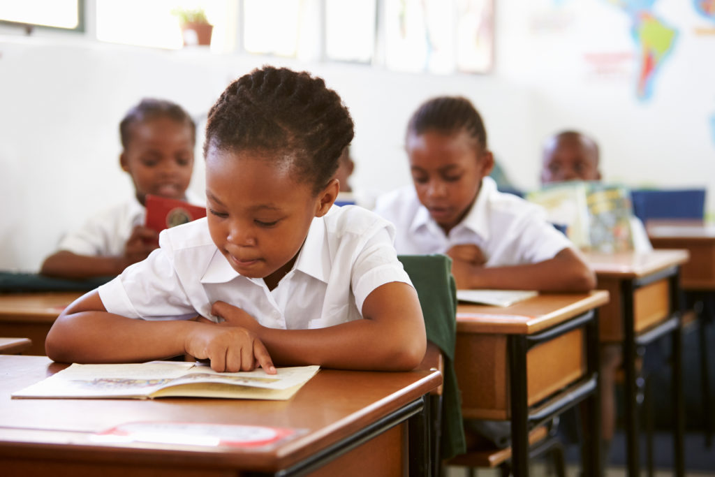 Black school children reading in classroom. 
